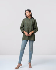 Woman wearing a green long-sleeve top and blue jeans on a white background